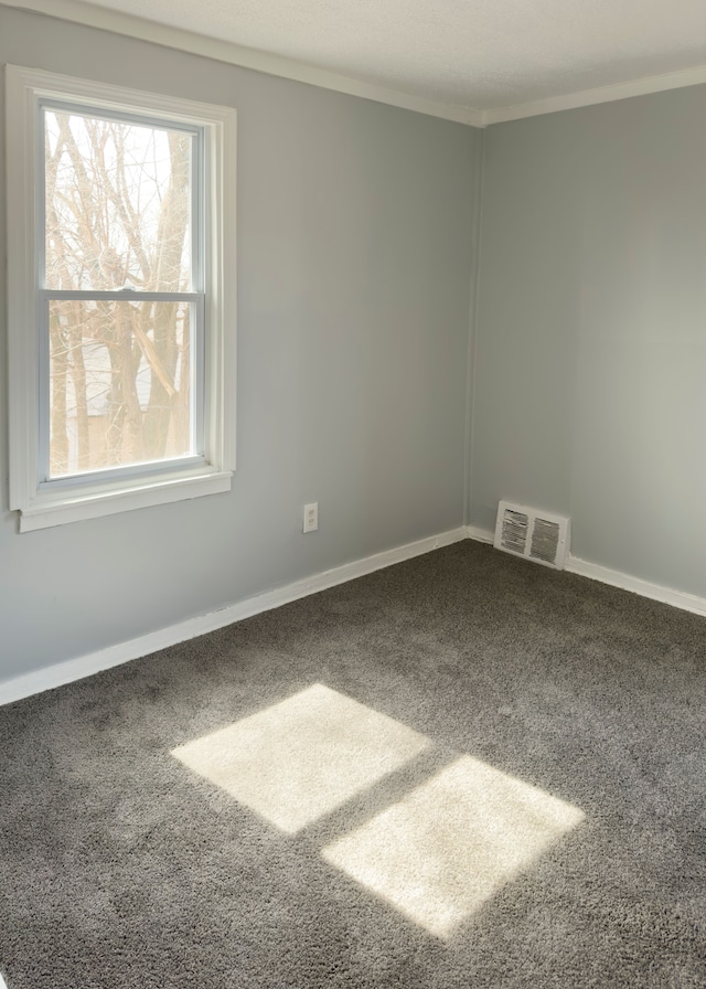 carpeted spare room featuring crown molding, baseboards, and visible vents