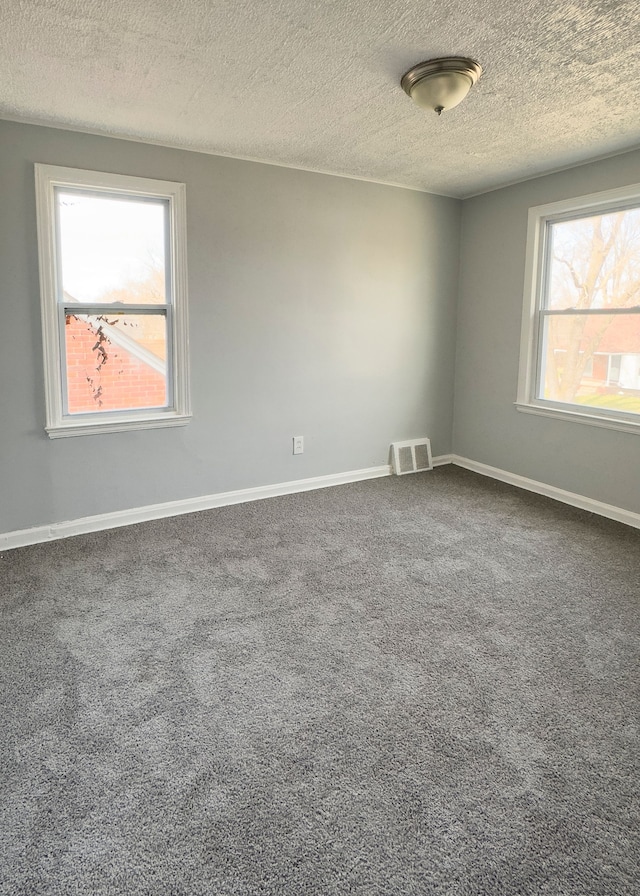 unfurnished room featuring baseboards, dark colored carpet, a textured ceiling, and visible vents