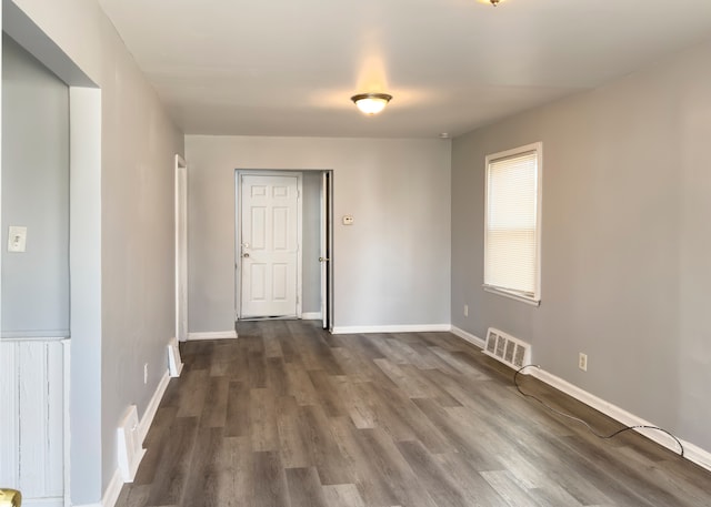 unfurnished room featuring dark wood-style floors, visible vents, and baseboards