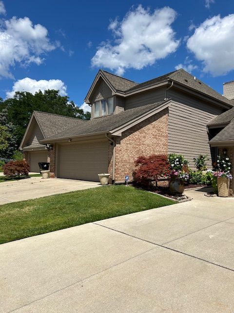 26766 Plumgrove Ln Unit 56, Farmington Hills, MI 48334 - view of side of home with brick siding, a garage, and concrete driveway