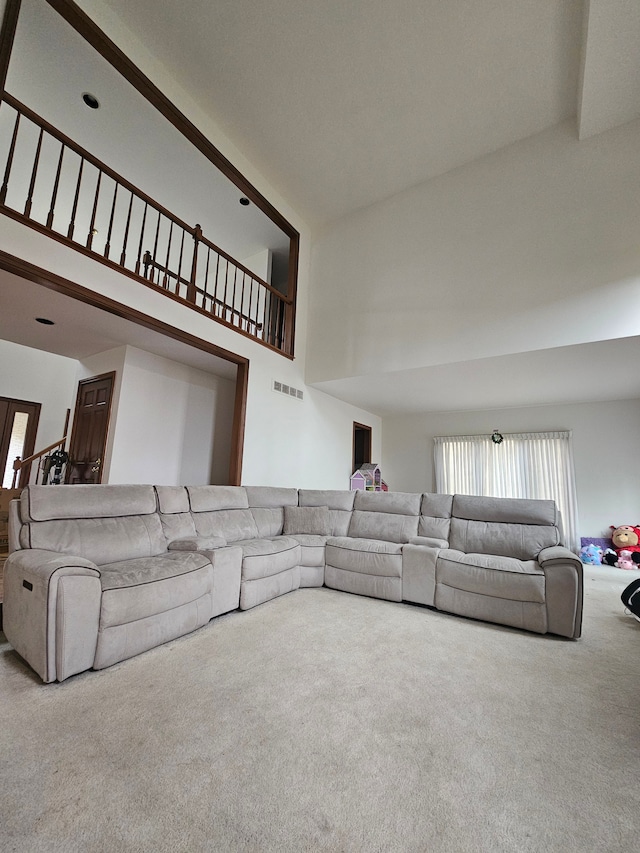 carpeted living area with a towering ceiling and visible vents