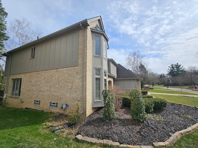 view of side of property featuring a yard, brick siding, and board and batten siding