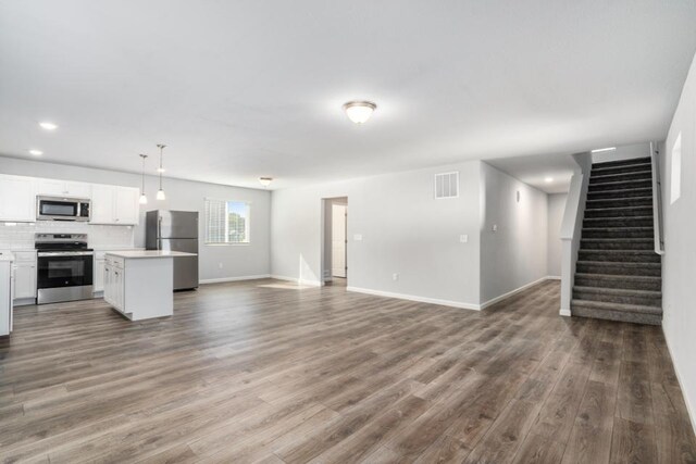 550 Needlewood Dr, Cedar Springs, MI 49319 - unfurnished living room with dark wood-style flooring, stairway, baseboards, and recessed lighting