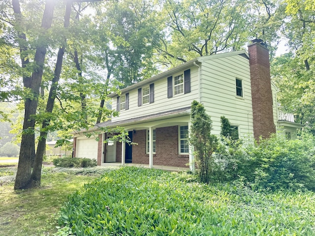 7325 Sheffield Dr SE, Ada, MI 49301 - view of front of property with an attached garage, a chimney, and brick siding