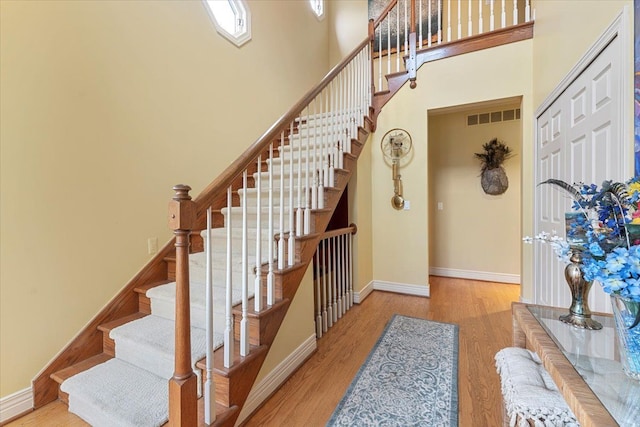 9283 Firwood Rd, South Lyon, MI 48178 - stairs with baseboards, visible vents, a high ceiling, and wood finished floors