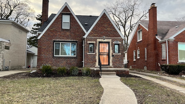 english style home featuring brick siding and a chimney