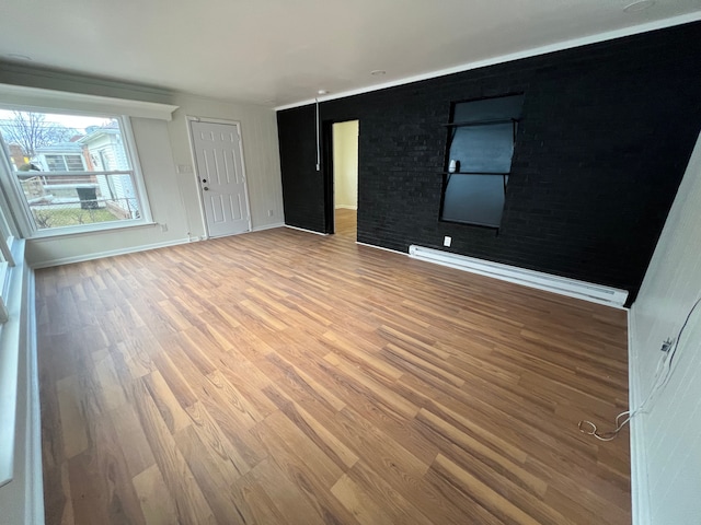 spare room featuring a baseboard heating unit, light wood-type flooring, and baseboards