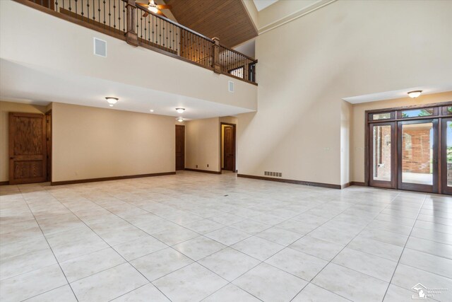 8650 Stone Rd, Maybee, MI 48159 - unfurnished living room with a towering ceiling, light tile patterned floors, and french doors