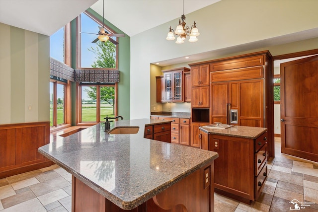 8650 Stone Rd, Maybee, MI 48159 - kitchen with a spacious island, high vaulted ceiling, brown cabinets, a chandelier, and glass insert cabinets