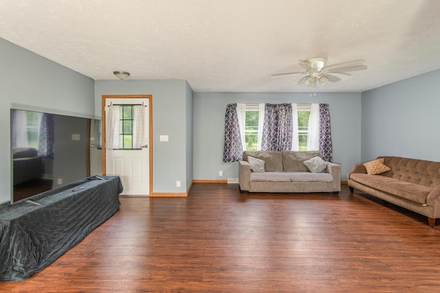 living room with a textured ceiling, baseboards, a ceiling fan, and wood finished floors