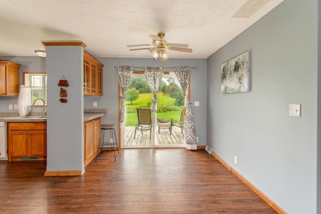 unfurnished dining area with dark wood-style flooring, a healthy amount of sunlight, a ceiling fan, and a sink