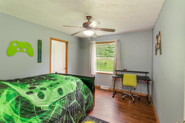 bedroom with visible vents, a textured ceiling, baseboards, and hardwood / wood-style floors