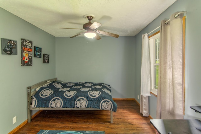 bedroom featuring a textured ceiling, baseboards, and wood finished floors