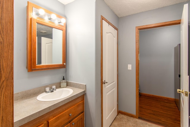 bathroom featuring a textured ceiling, vanity, and baseboards