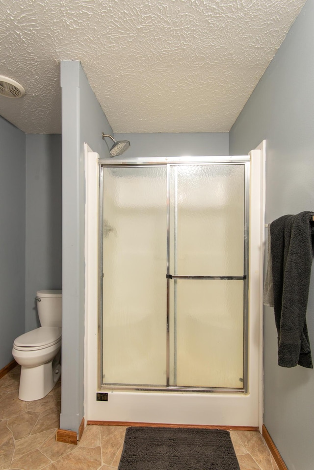 full bathroom with visible vents, toilet, a textured ceiling, a shower stall, and baseboards