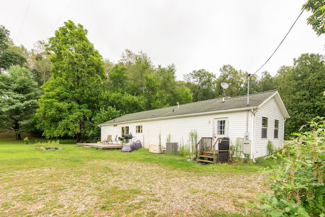 rear view of house featuring a deck, cooling unit, and a yard