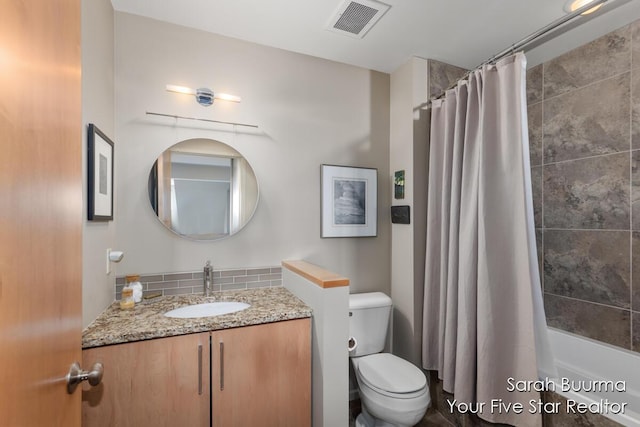 bathroom with visible vents, toilet, vanity, shower / bath combo with shower curtain, and backsplash