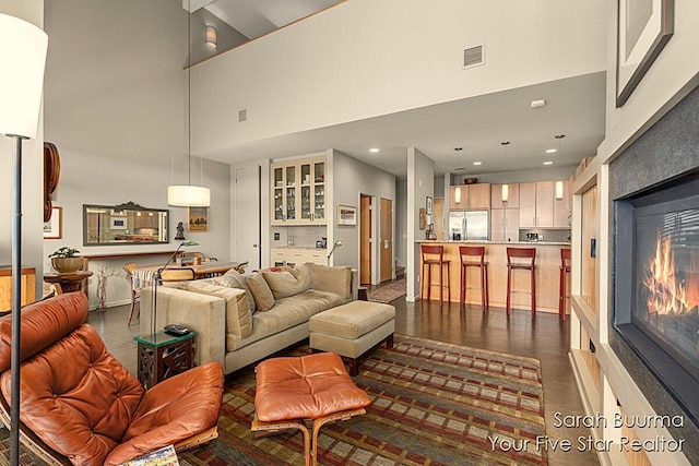 living area featuring a high ceiling, recessed lighting, and visible vents