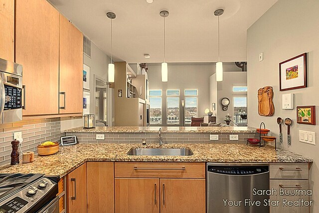 kitchen with stainless steel appliances, light stone countertops, decorative backsplash, a sink, and a peninsula