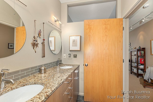 ensuite bathroom with double vanity, a sink, track lighting, and connected bathroom
