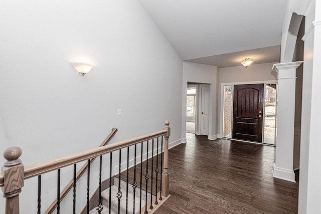 entrance foyer with vaulted ceiling, decorative columns, baseboards, and dark wood-style flooring