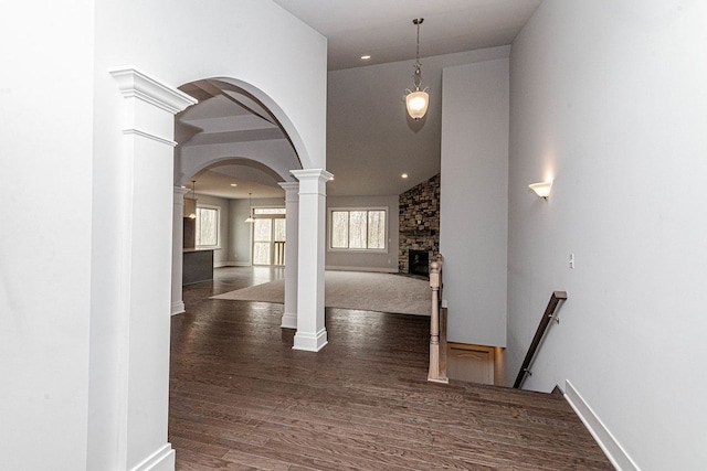 entrance foyer with dark wood finished floors, decorative columns, baseboards, and arched walkways