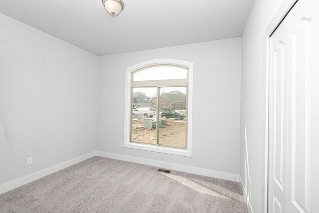 empty room featuring carpet, visible vents, and baseboards