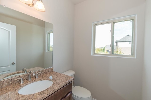 bathroom with plenty of natural light, toilet, and vanity