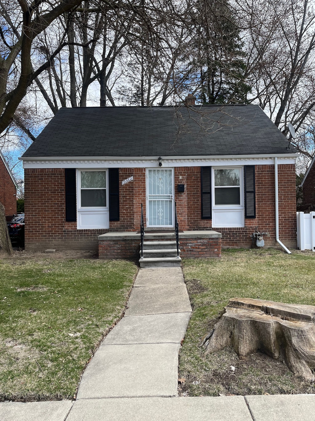19362 Braile St, Detroit, MI 48219 - view of front facade featuring entry steps, brick siding, a front yard, and a shingled roof