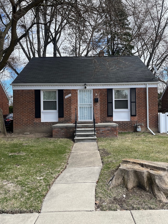 19362 Braile St, Detroit, MI 48219 - view of front facade featuring entry steps, brick siding, a front yard, and a shingled roof