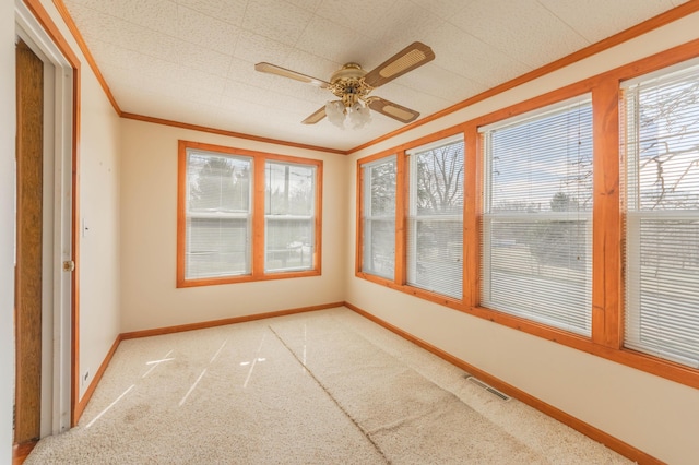 unfurnished sunroom featuring crown molding, carpet, and baseboards