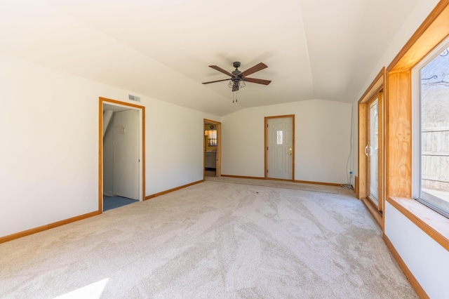 empty room featuring light colored carpet, vaulted ceiling, a ceiling fan, and baseboards