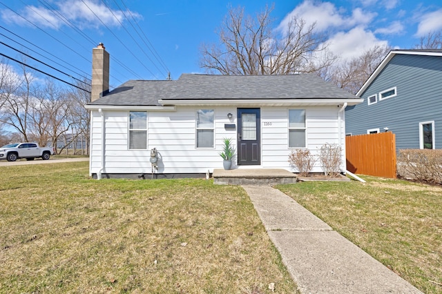 bungalow-style home featuring a front lawn, a chimney, fence, and roof with shingles
