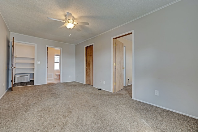 unfurnished bedroom featuring carpet floors, ornamental molding, a wall mounted air conditioner, and a textured ceiling