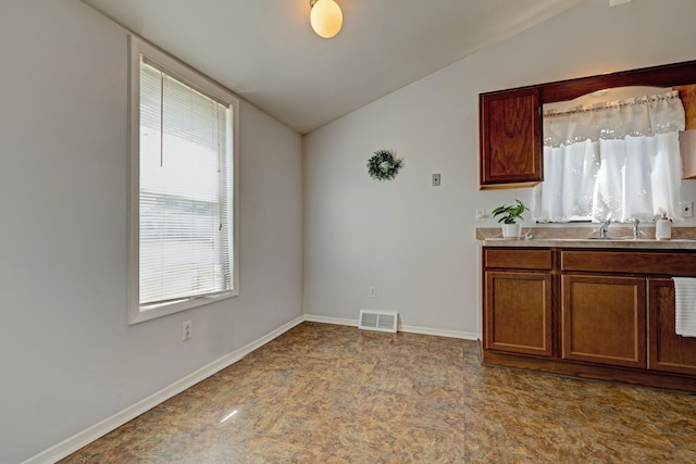 interior space featuring light countertops, lofted ceiling, baseboards, a sink, and visible vents
