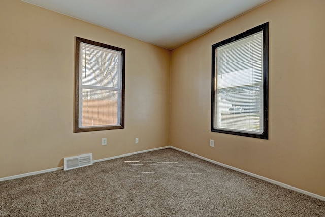 unfurnished room with plenty of natural light, baseboards, visible vents, and carpet