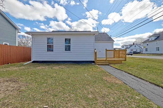 rear view of house featuring a yard, a deck, and fence