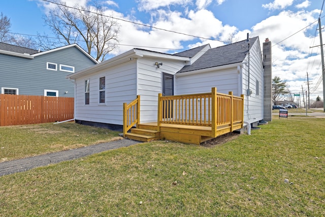 back of house with a lawn, a chimney, fence, and a wooden deck