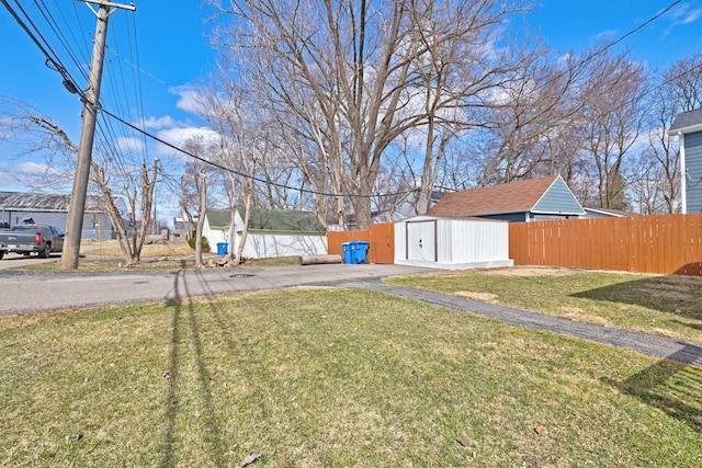 view of yard with an outdoor structure, a storage unit, and fence