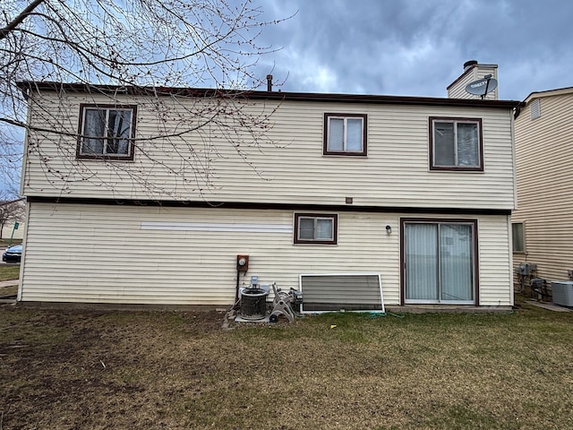 rear view of house with a lawn, a chimney, and central AC