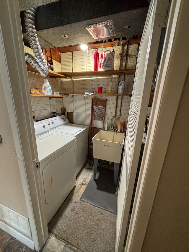 clothes washing area with washing machine and dryer and a sink