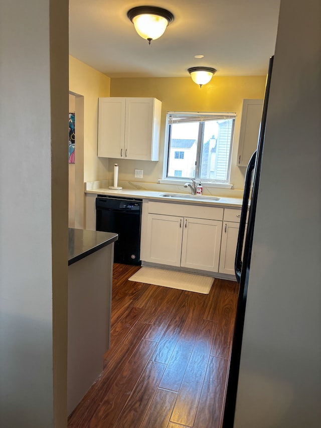 kitchen with a sink, freestanding refrigerator, dishwasher, dark wood-style floors, and white cabinets