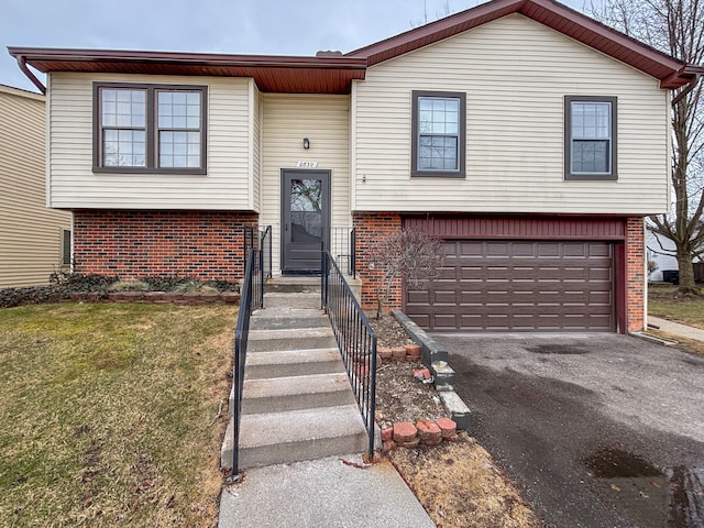 split foyer home with driveway, brick siding, and a garage