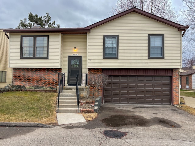 raised ranch featuring brick siding, a garage, and aphalt driveway