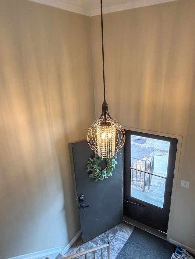 entryway with baseboards, ornamental molding, and a notable chandelier