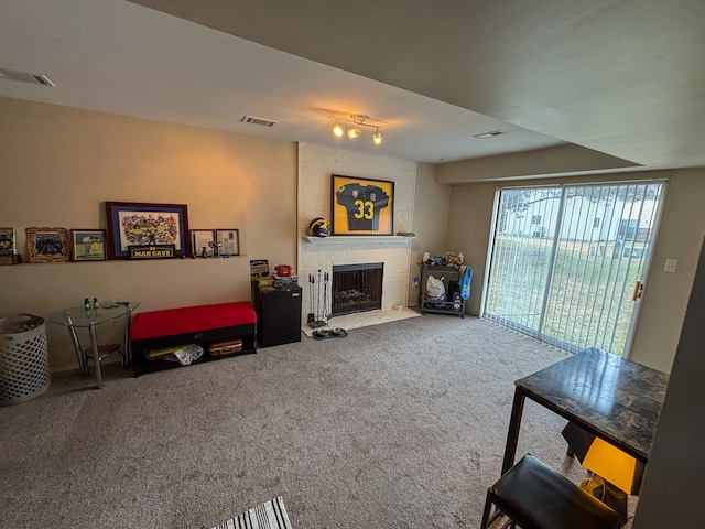 living area featuring rail lighting, a brick fireplace, carpet floors, and visible vents