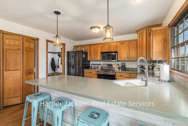 kitchen with brown cabinets, a sink, stainless steel appliances, a kitchen bar, and a peninsula