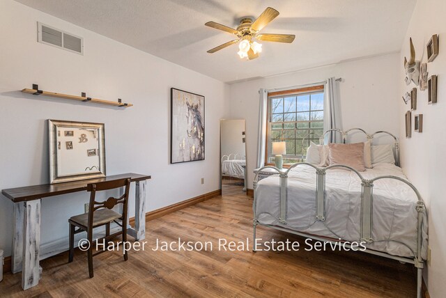 bedroom featuring baseboards, visible vents, wood finished floors, and ceiling fan
