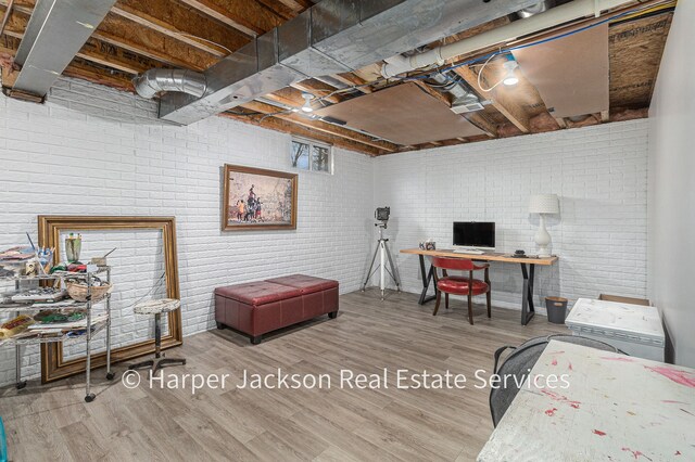 office featuring wood finished floors and brick wall