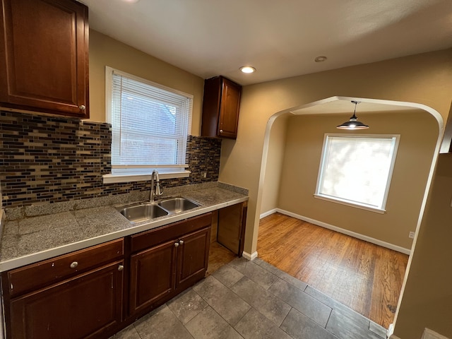 10026 Coyle St, Detroit, MI 48227 - kitchen featuring baseboards, arched walkways, tile countertops, a sink, and backsplash